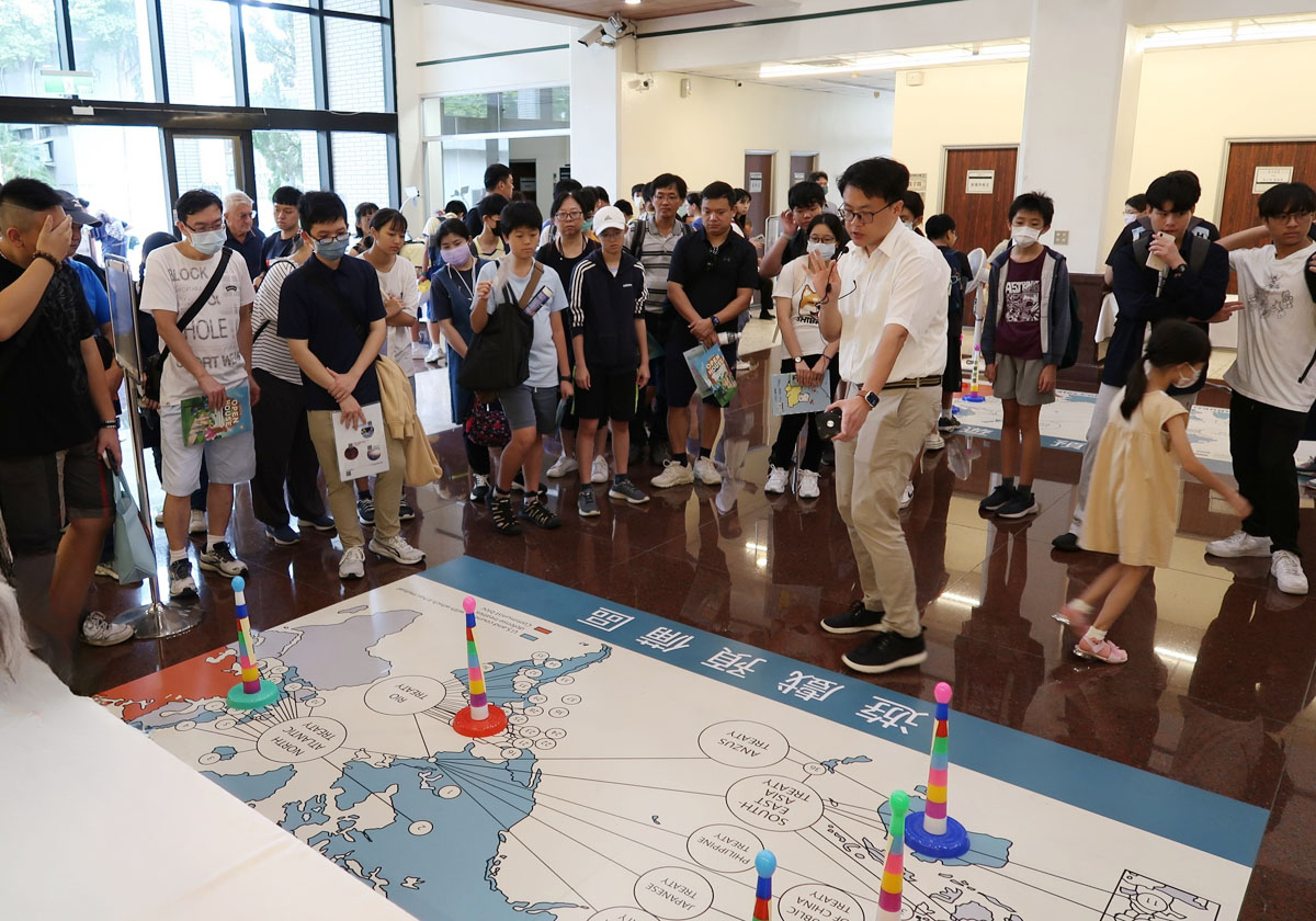 圖一：近史所助研究員陳冠任（中持麥克風者）於活動中進行導覽與互動解說，旁為民眾參與。